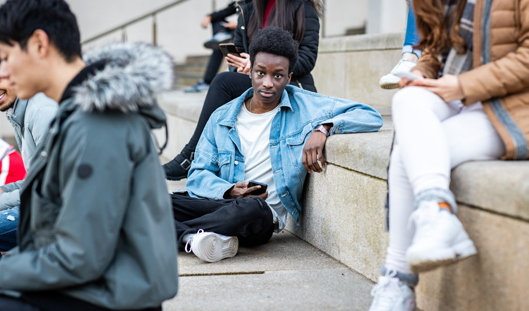 young man looking up from his cell phone