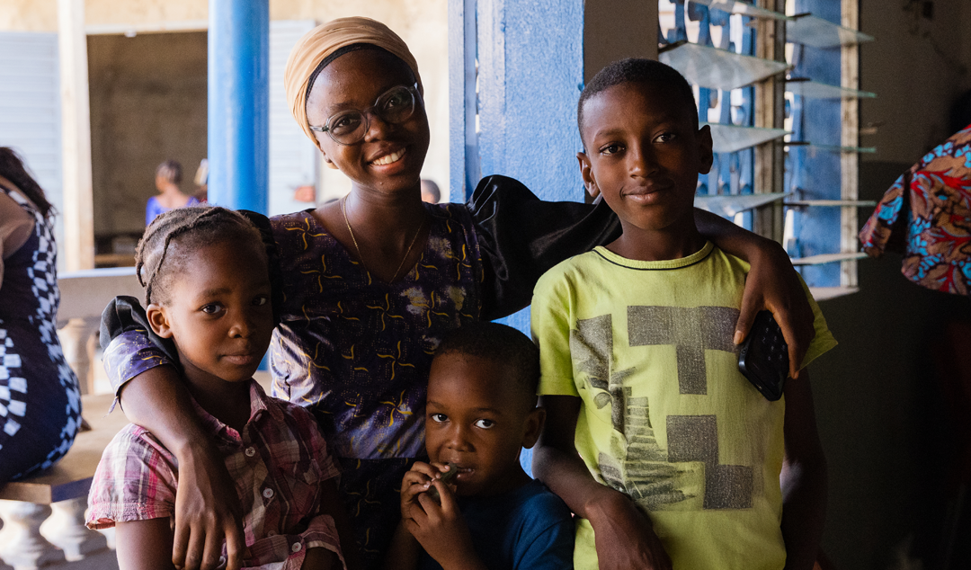 a woman smiling with her arms around three kids