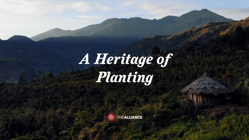Mountain landscape at sunrise with a small thatched-roof hut in the foreground and the text “A Heritage of Planting” centered on the image.