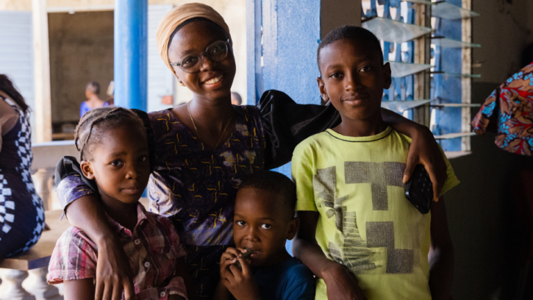 a woman smiling with her arms around three kids