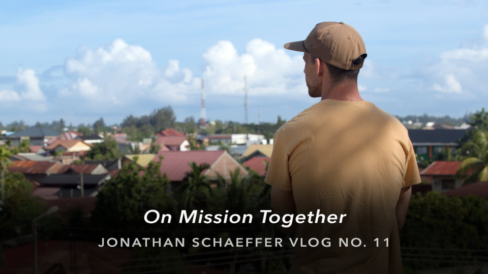 Person in a tan shirt and cap overlooks a town with rooftops and palm trees; text reads “On Mission Together, Jonathan Schaeffer Vlog No. 11.”
