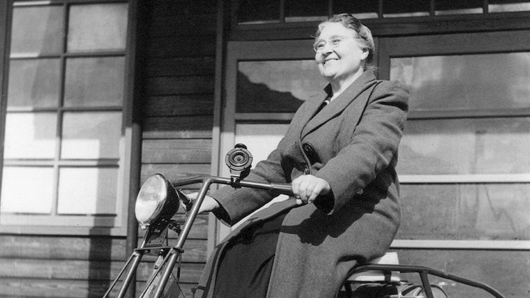 Black and white photo of Mabel Francis riding a motorcycle